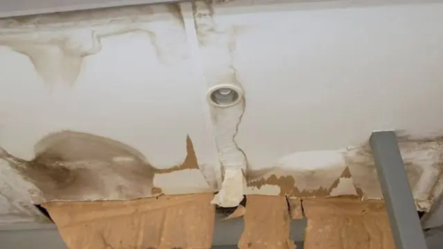 Water-stained ceiling with a leak coming from around a light fixture